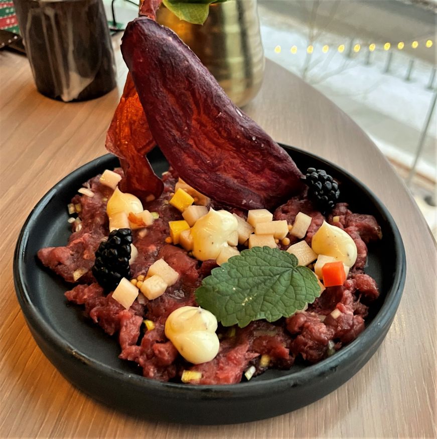 Venison tartare garnished with vegetables and sauces