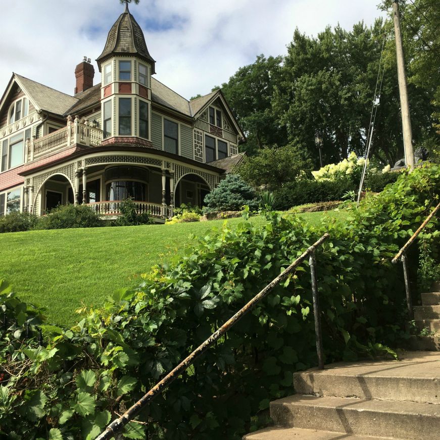 Cement steps in the foreground with a colorful Queen Anne-style mansion in the background