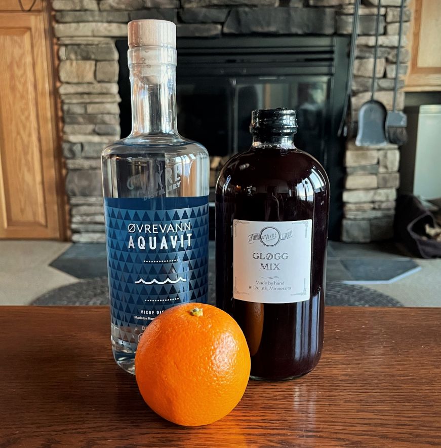 Bottle of Vikre Distillery aquavit, bottle of glogg mix, and an orange