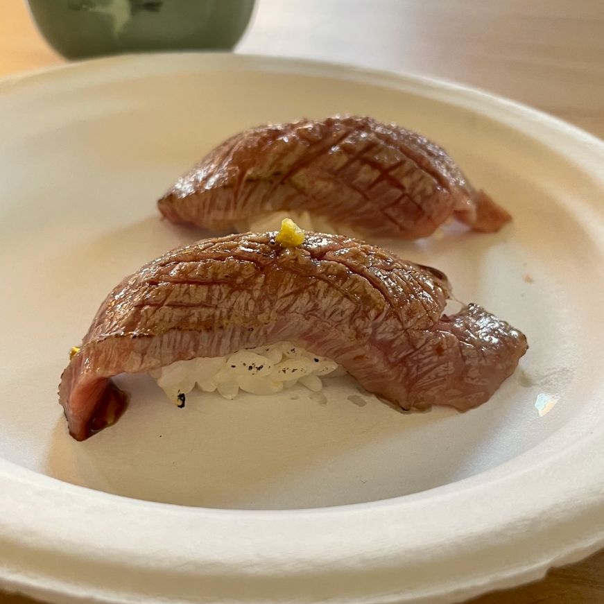 Two pieces of wagyu nigiri on a paper plate