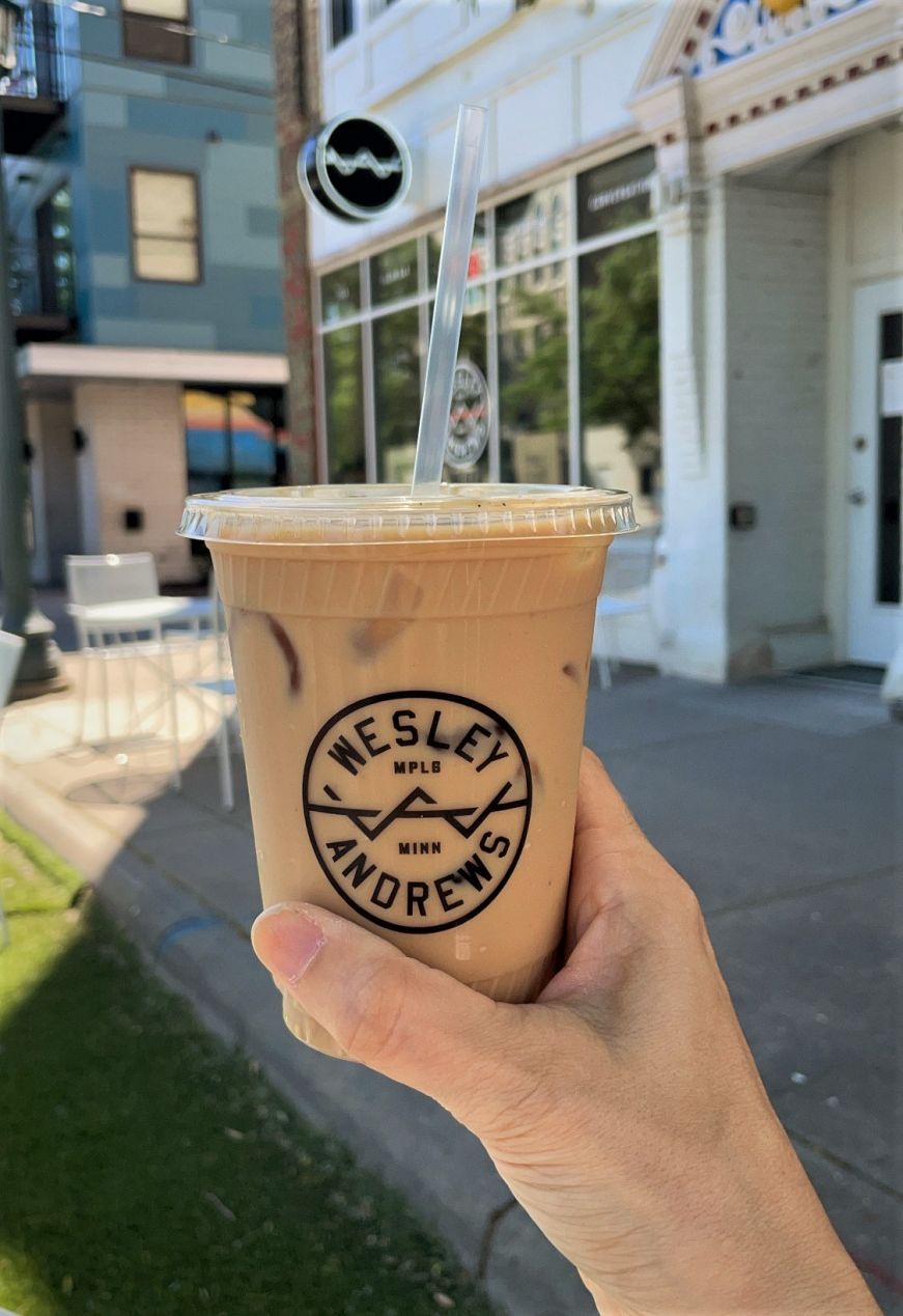 Hand holding an iced coffee drink in a plastic cup