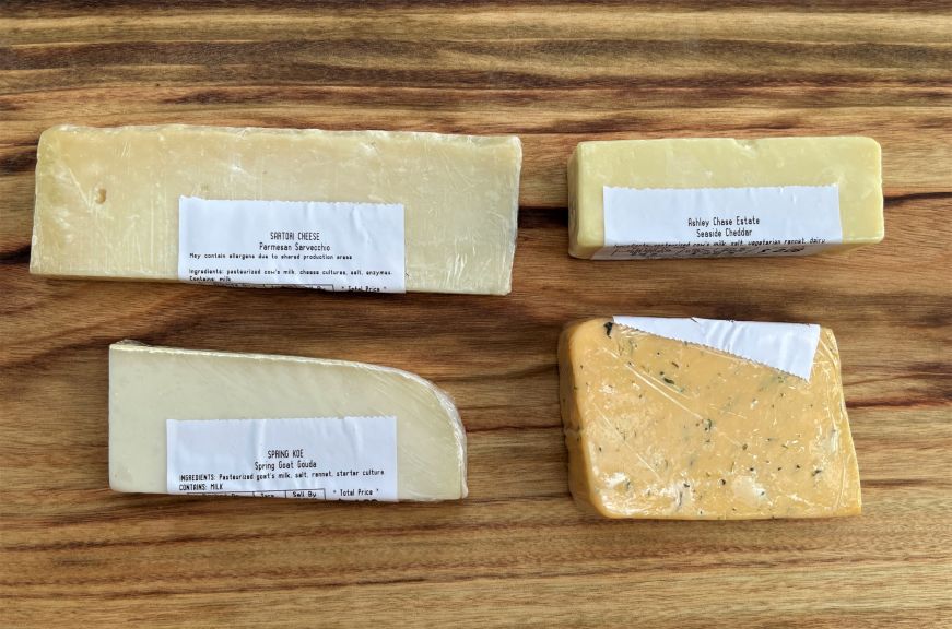 Small wrapped blocks of cheese on a wooden cutting board