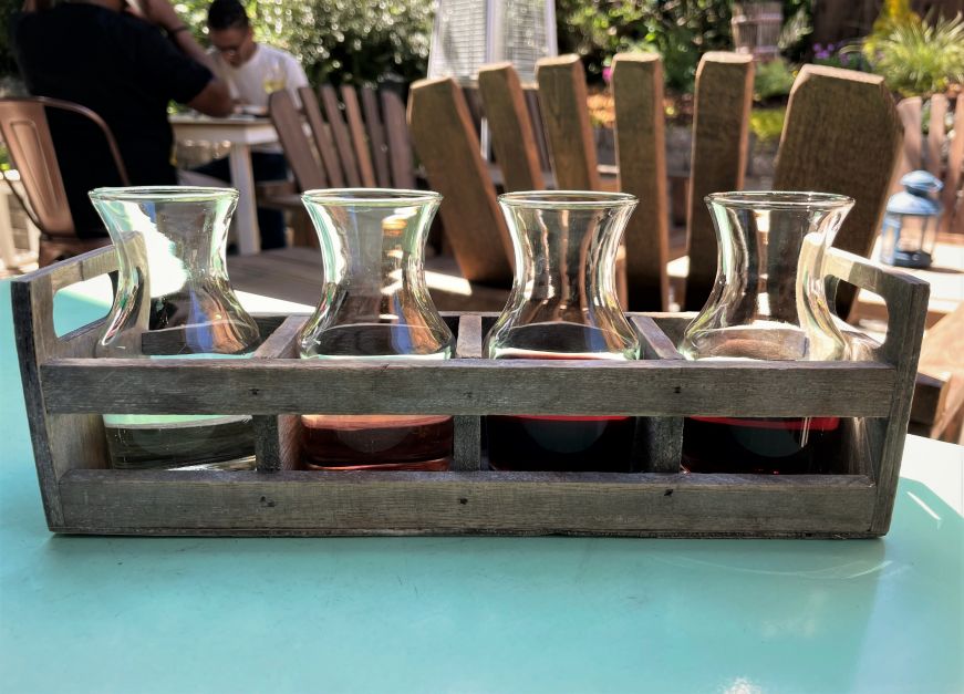 Four small glass carafes filled with white and red wines