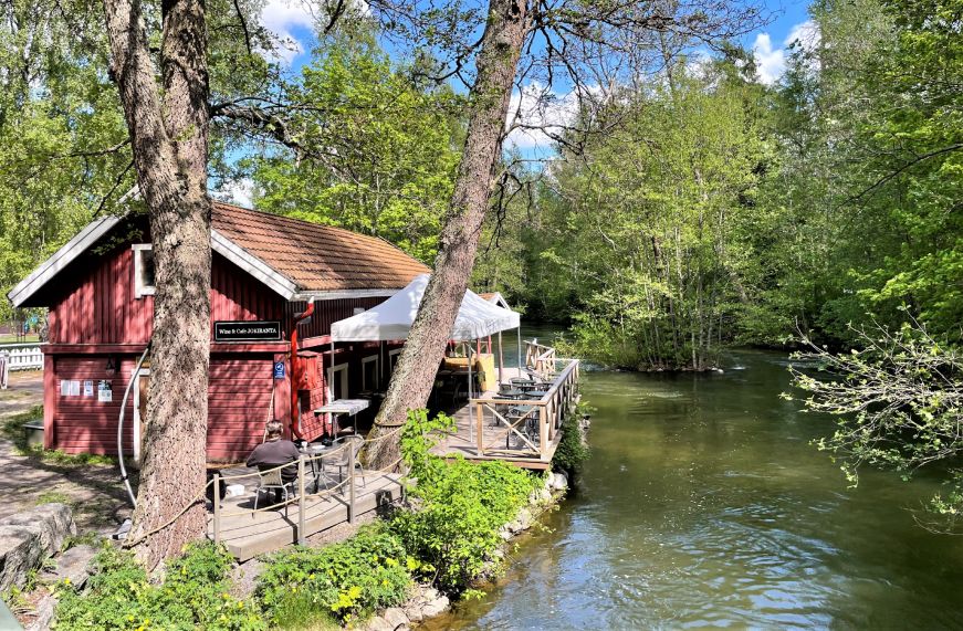 Red wooden cafe with a deck overlooking a river