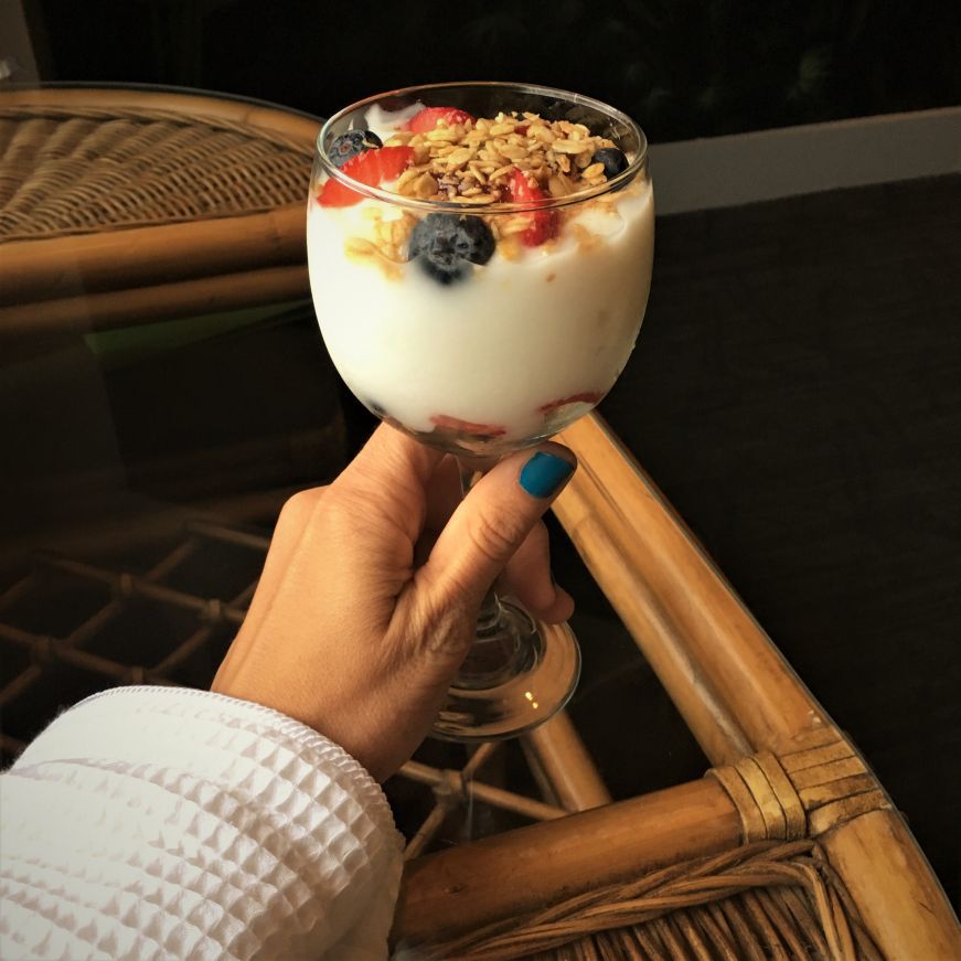 Hand holding yogurt parfait in wine glass, Chateau Avalon, Kansas City, Kansas