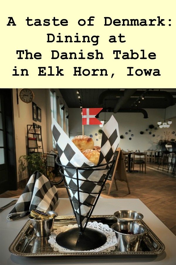 Cone-shaped container of fried dough spheres garnished with a small Danish flag and the text A Taste of Denmark at The Danish Table in Elk Horn, Iowa 