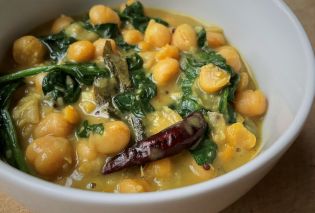 Bowl filled with chickpeas and spinach in a yellow sauce