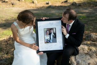 Stacy and Mike looking at a large framed wedding photo
