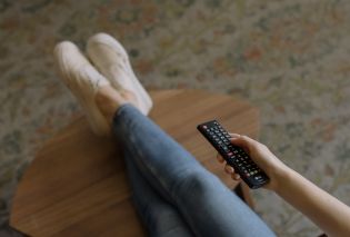 Legs propped up on coffee table and hand holding remote