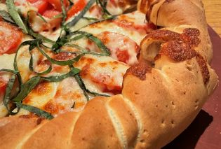 Close up view of a margherita pizza with a rolled edge crust