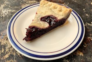 Slice of blackberry pie on a white plate with a blue border