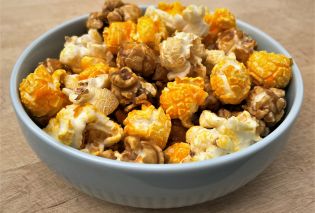 Blue ceramic bowl filled with a mixture of cheese, seasoned, and caramel popcorn