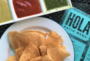 Serving dish with three types of salsa, chips, and menu