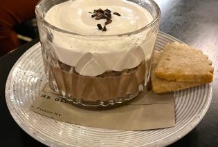 Small bowl of chocolate pudding topped with whipped cream and served with two small cookies