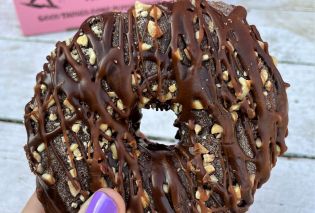 Raised doughnut topped with chocolate frosting and peanuts