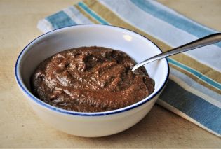 Cornmeal Molasses Pudding in bowl with spoon and napkin in background