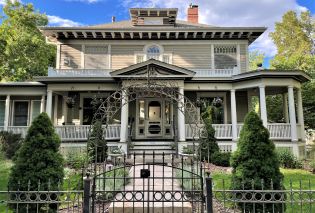 Exterior of two-story beige Victorian house with a porch