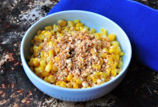 Bowl of corn topped with grated cheese and chipotle powder