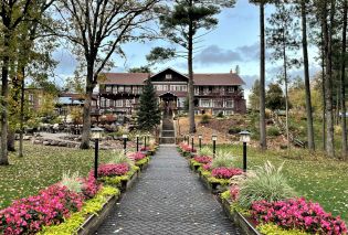 Flower lined path leading a large log-construction lodge building 