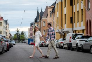 Stacy and Mike walking across a street in Helsinki with colorful buildings in the background