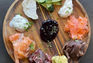 Wooden platter with cured meats, fish, cheeses, and jams