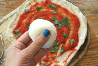 Hand holding mozzarella over uncooked pizza, 1889 Pizza Napoletana, Kansas City, Kansas