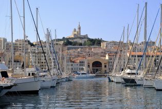 Marina filled with sailboats with a church on a hill in the background