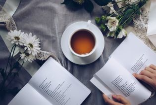 Top down view of table with books, flowers, and cup of tea