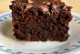 Piece of chocolate cake on a white plate with a blue border