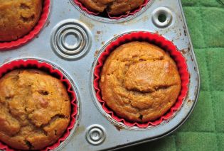 Pumpkin muffins in a tin with a green potholder