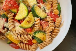Bowl filled with rotini pasta with sauteed zucchini, fresh tomatoes, and grated Parmesan