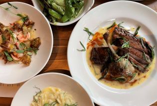 Top down view of dishes of prawns, snap peas, roasted duck, and orzo