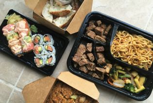 Takeout boxes of sushi, gyoza, and a hibachi steak dinner