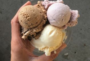 Hand holding plastic dish with three small scoops of ice cream