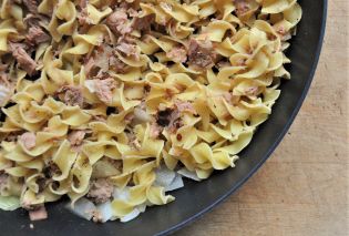 Close up of egg noodles and canned tuna in a skillet