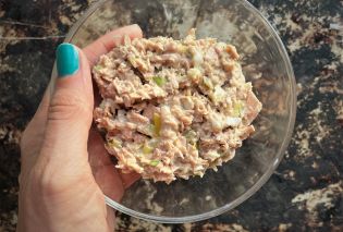 Hand holding glass bowl filled with tuna salad