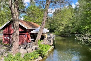 Red wooden cafe with a deck overlooking a river